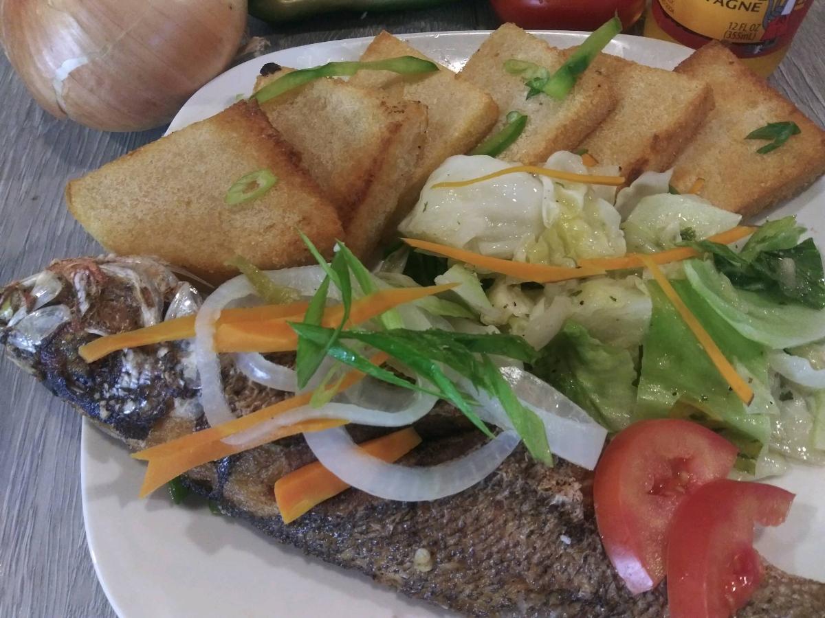 2 Escovitch Fried Fish Served With Banmmy (Feeds 2)- accompanied by our delicious Banmmy. Perfect for 2 people, it's a traditional dish that offers a tangy, crispy texture and a burst of Jamaican flavors. Experience a taste of the islands with every bite.