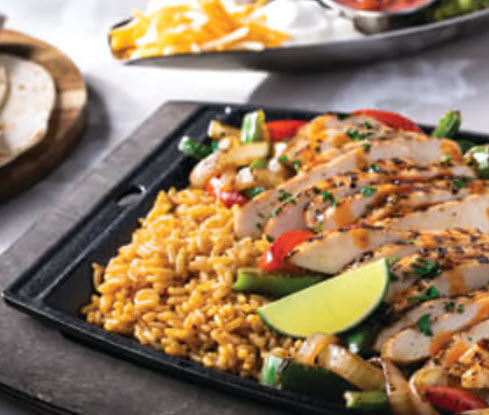 Wicked Chicken Fajitas! Made with tender grilled chicken, sauteed onions and peppers, and topped with fresh toppings like guacamole, sour cream, cheese, and pico de gallo. Served with a side of rice and beans