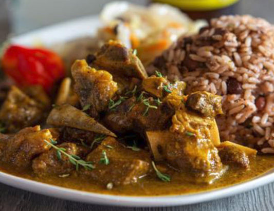 Curry Goat Dinner complete with tender goat meat, stewed cabbage, rice and peas, and sweet plantains. A traditional Jamaican dish bursting with spice and flavor.